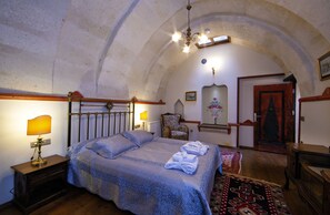 Un dormitorio con una cama, dos lámparas de noche, una silla, una puerta y un candelabro.