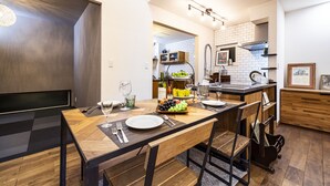 A modern kitchen with a dining area, featuring a wooden table, chairs, and a fruit bowl. - Antiques Inuyama (Inuyama)