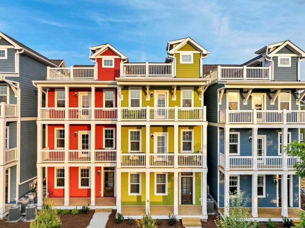 Una hilera de edificios residenciales de varios pisos con balcones y un paseo central.