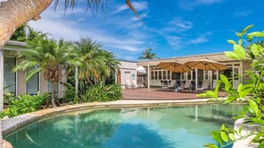 A pool area with lounge chairs and umbrellas, surrounded by palm trees and a building with large windows. - The Byron Pavilion - Nestled in the heart of Byron, park the car and walk everywhere. (Byron Bay)