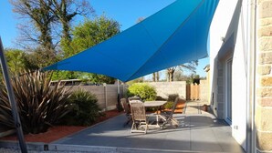 A patio with a blue shade sail, a round table, and chairs. - Modern house with bikes, near Sartilly trails (Sartilly)