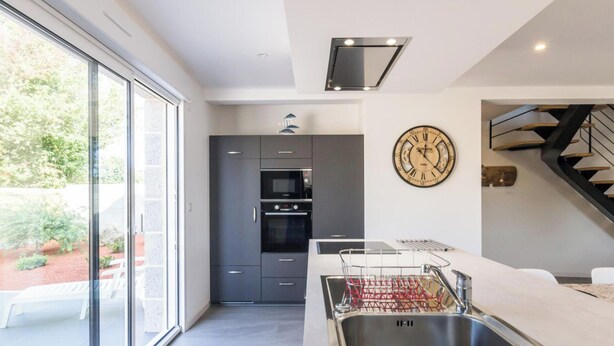 A modern kitchen with a built-in oven, a large window, and a clock on the wall. - Modern house with bikes, near Sartilly trails (Sartilly)