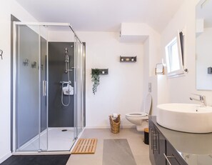 A modern bathroom with a glass shower enclosure, a white sink, and a toilet. - Modern house with bikes, near Sartilly trails (Sartilly)