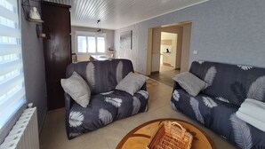 Ein modernes Wohnzimmer mit zwei Sofas, einem Esstisch und einer Küche im Hintergrund.