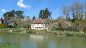 Ein Haus an einem ruhigen Fluss unter einem wolkenlosen Himmel.