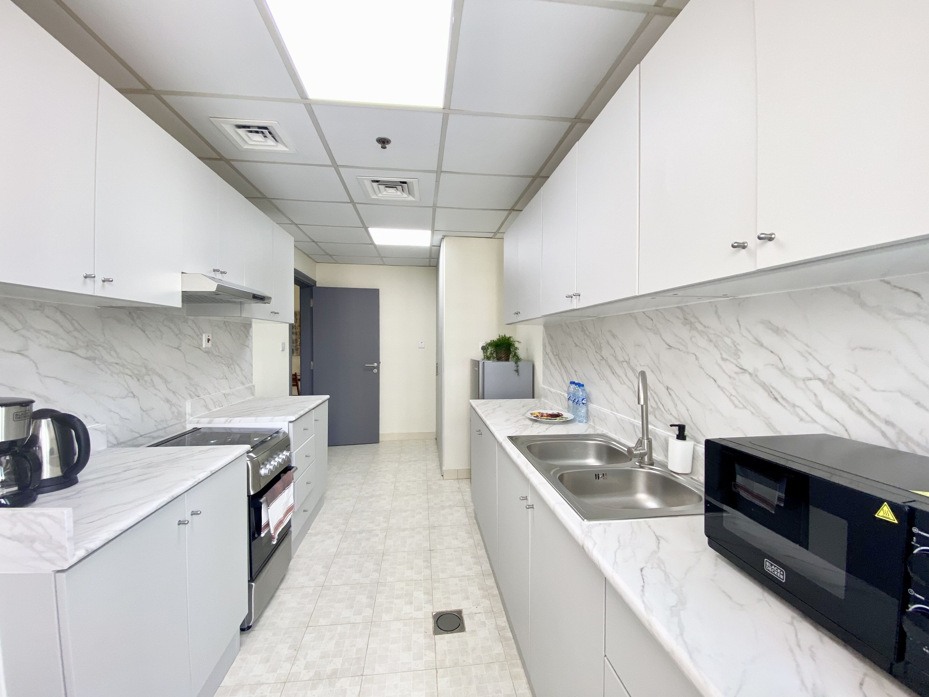 A modern kitchen with white cabinets, a stainless steel sink, a microwave, and a stove.