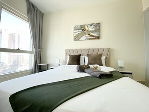 A hotel room with a large bed, a view of the city, and a painting on the wall.