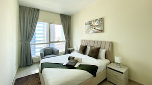 Een moderne hotelkamer met een groot bed, een nachtkastje, een stoel en een raam met gordijnen.