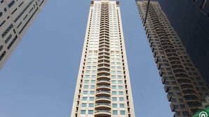 Een hoog, modern gebouw met een centraal kernstuk en balkons.