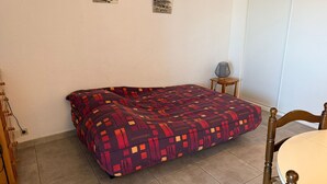 Une chambre à coucher avec un lit, une petite table sur laquelle se trouve une lampe, et deux tableaux encadrés accrochés au mur.