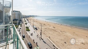 A beach with a clear view of the sea and buildings in the background. - Modern 80m² apartment with wifi, dishwasher, balcony, and sea view (Les Sables-d'Olonne)