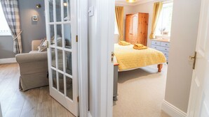 Een slaapkamer met een bed, een kledingkast, een stoel en een deur naar een andere kamer.