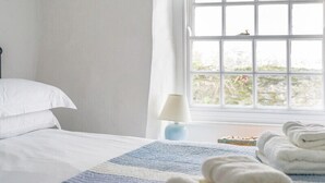 Un dormitorio con cama, ventana con vistas y lámpara en una mesita de noche.
