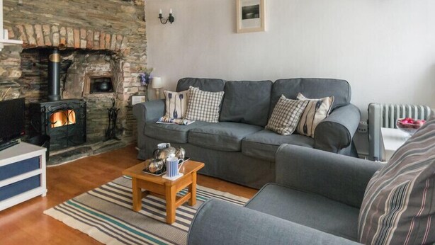 Una sala de estar acogedora con chimenea de piedra, un sofá gris y una mesa de centro de madera.