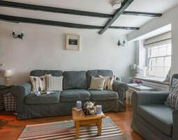 Un salón acogedor con un sofá gris, una mesa de centro de madera y una ventana con vistas.