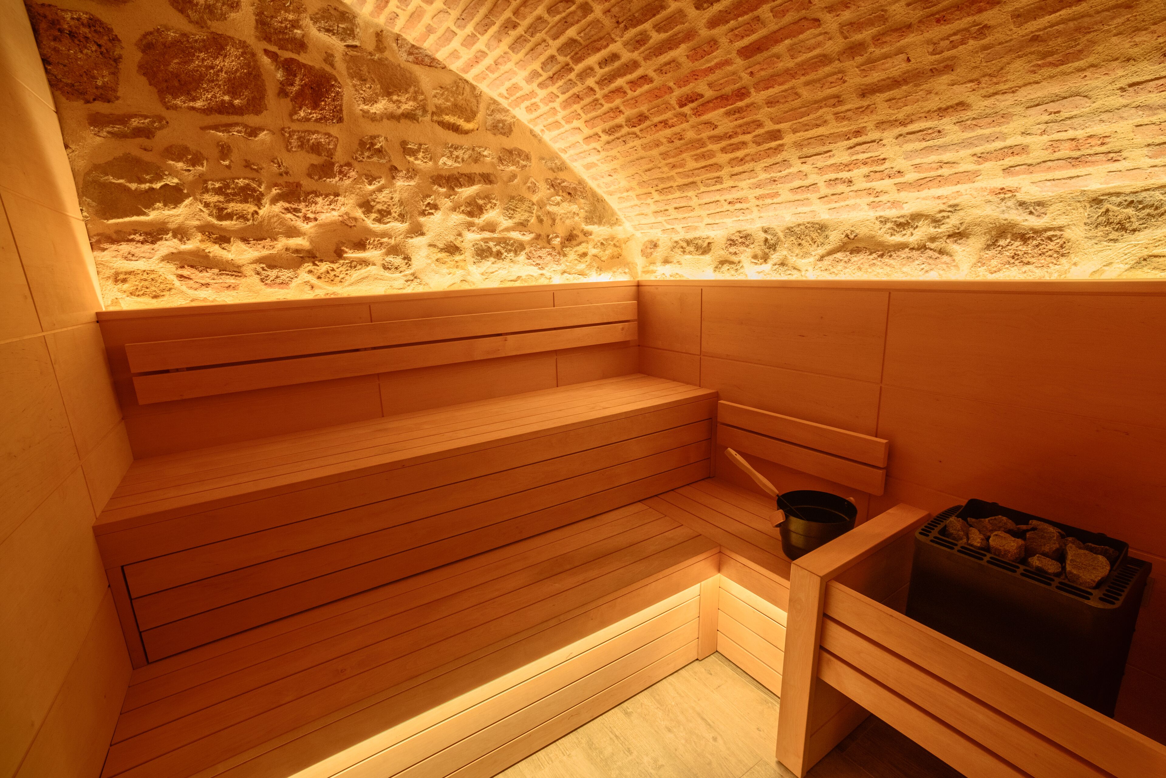 A sauna with wooden benches and a stone wall.