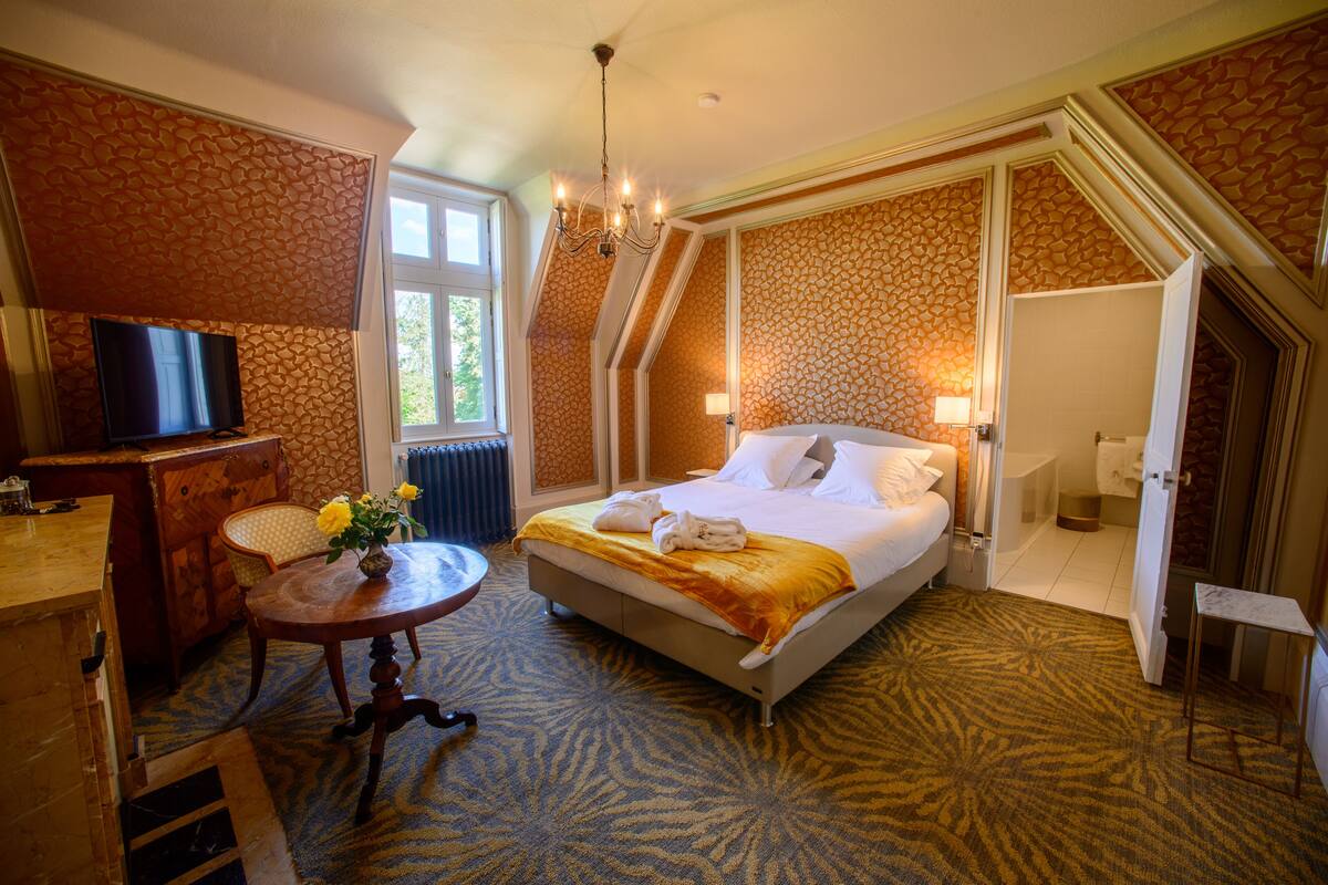 A hotel room with a bed, a TV, a desk, and a chair.
