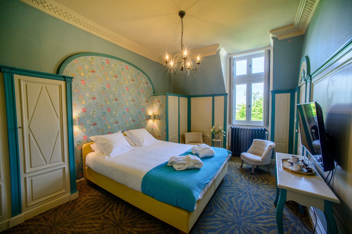 A hotel room with a large bed, a desk with a tray of breakfast items, a chair, and a television.
