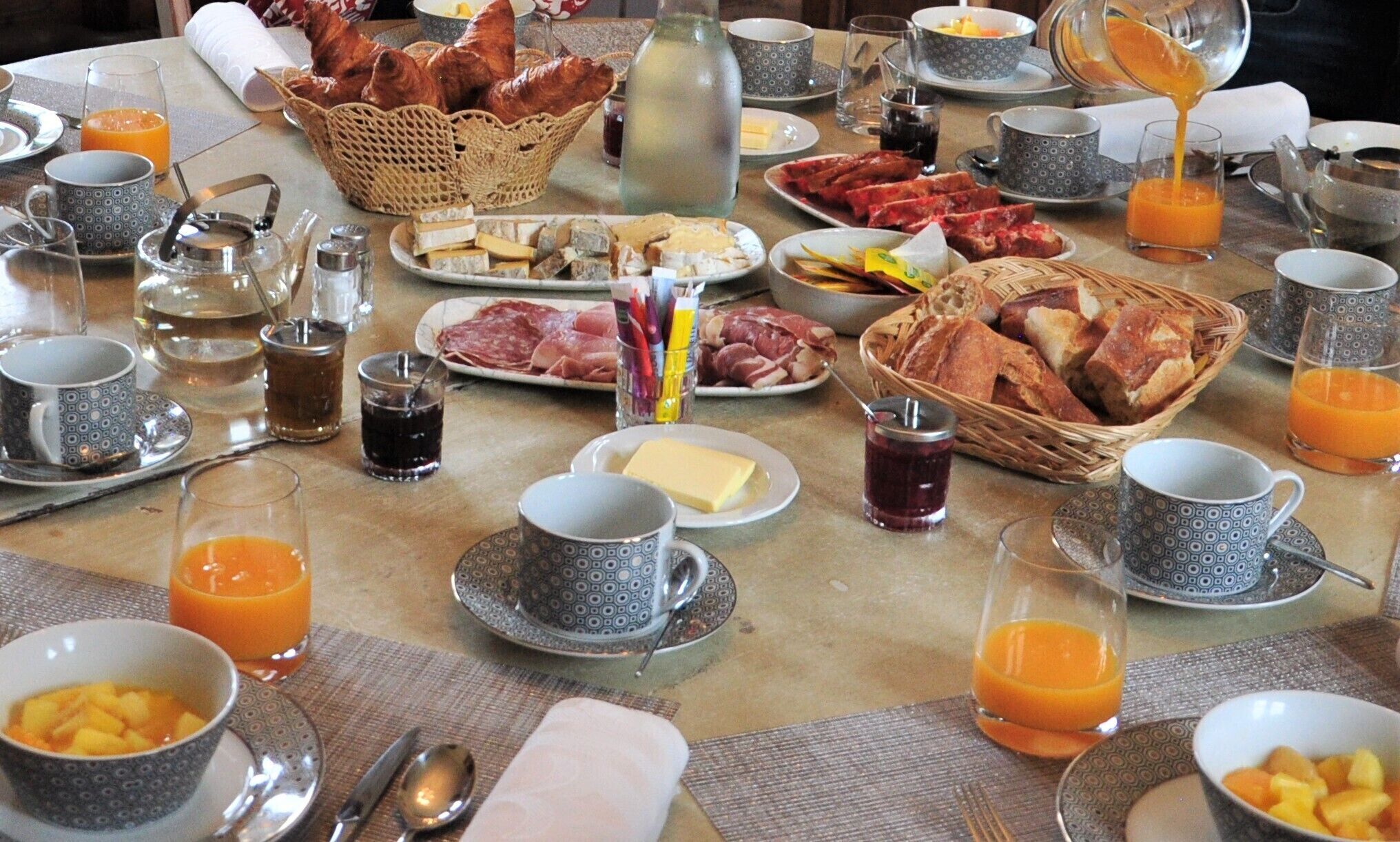 Et morgenbord med forskellige spiser, drikkevarer og bestik.