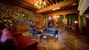 Un salon spacieux avec un plafond en bois, un canapé en cuir rouge, un canapé en cuir noir et une table basse en bois sur laquelle sont posés des magazines.