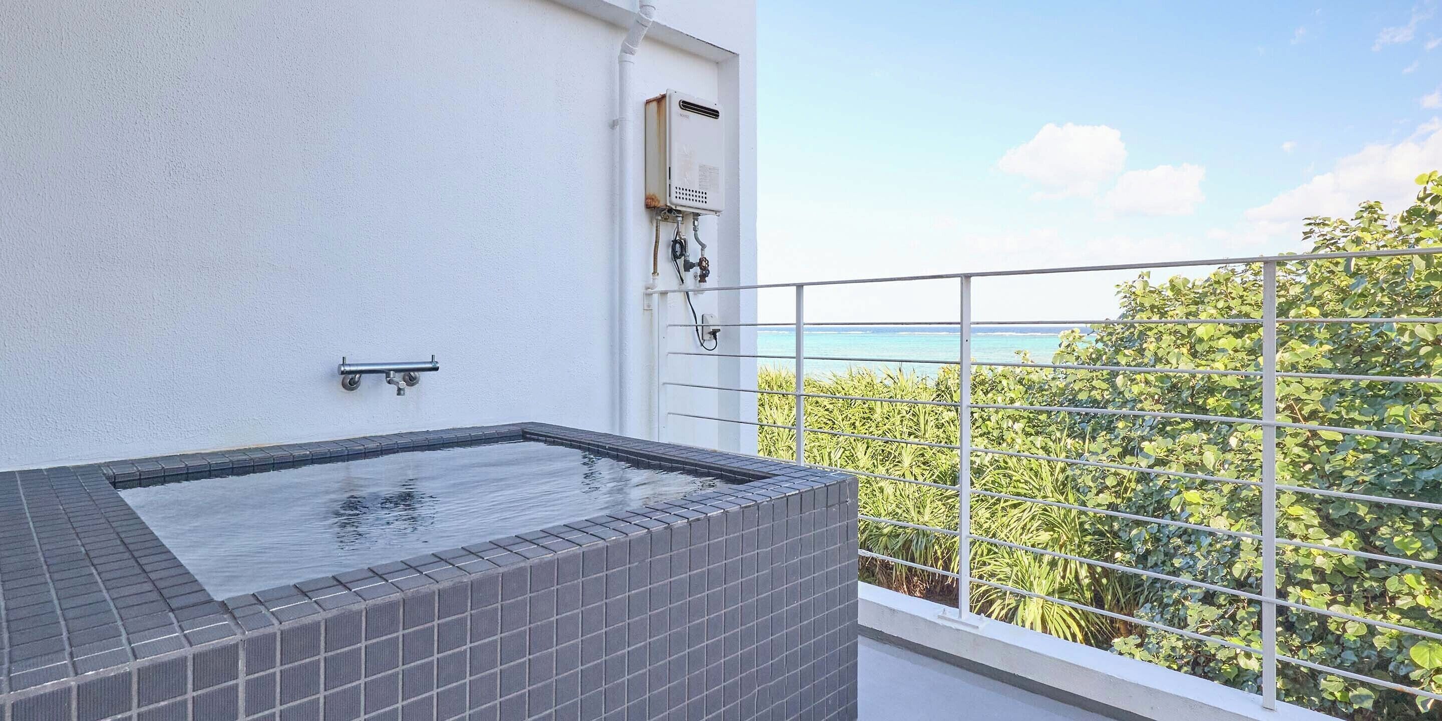 Un jacuzzi sur le toit offrant une vue sur la mer et la verdure.