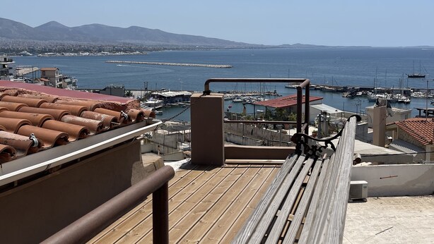 A wooden deck with a bench, overlooking a marina with boats and a distant mountain range. - Piraeus House With Sea View and Free Parking (Piraeus)