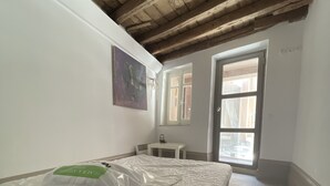 A room with a wooden ceiling, a bed with a mattress and pillows, a small table, a window, and a painting on the wall. - Piraeus House With Sea View and Free Parking (Piraeus)