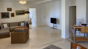 Ein geräumiges Wohnzimmer mit Sofa, Couchtisch, Fernseher und einer Kandelaber.