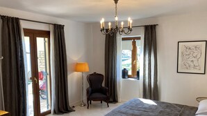 Ein Schlafzimmer mit einem großen Bett, einem Sessel, einer Stehlampe und einem Kronleuchter.