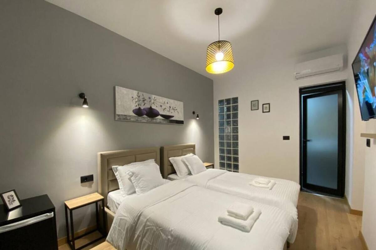 A modern hotel room with a large bed, bedside tables, a painting on the wall, and a television.