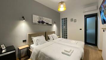 Une chambre d’hôtel moderne avec un grand lit, des tables de chevet, un tableau au mur et un téléviseur.