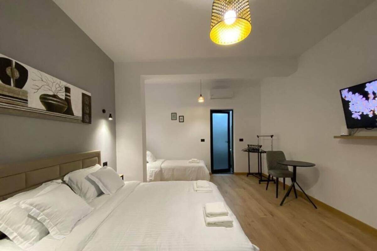 A hotel room with two beds, a TV, a small table, and a chair.