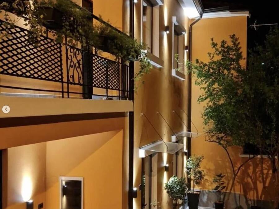 A multi-story building with balconies, outdoor lighting, and potted plants.