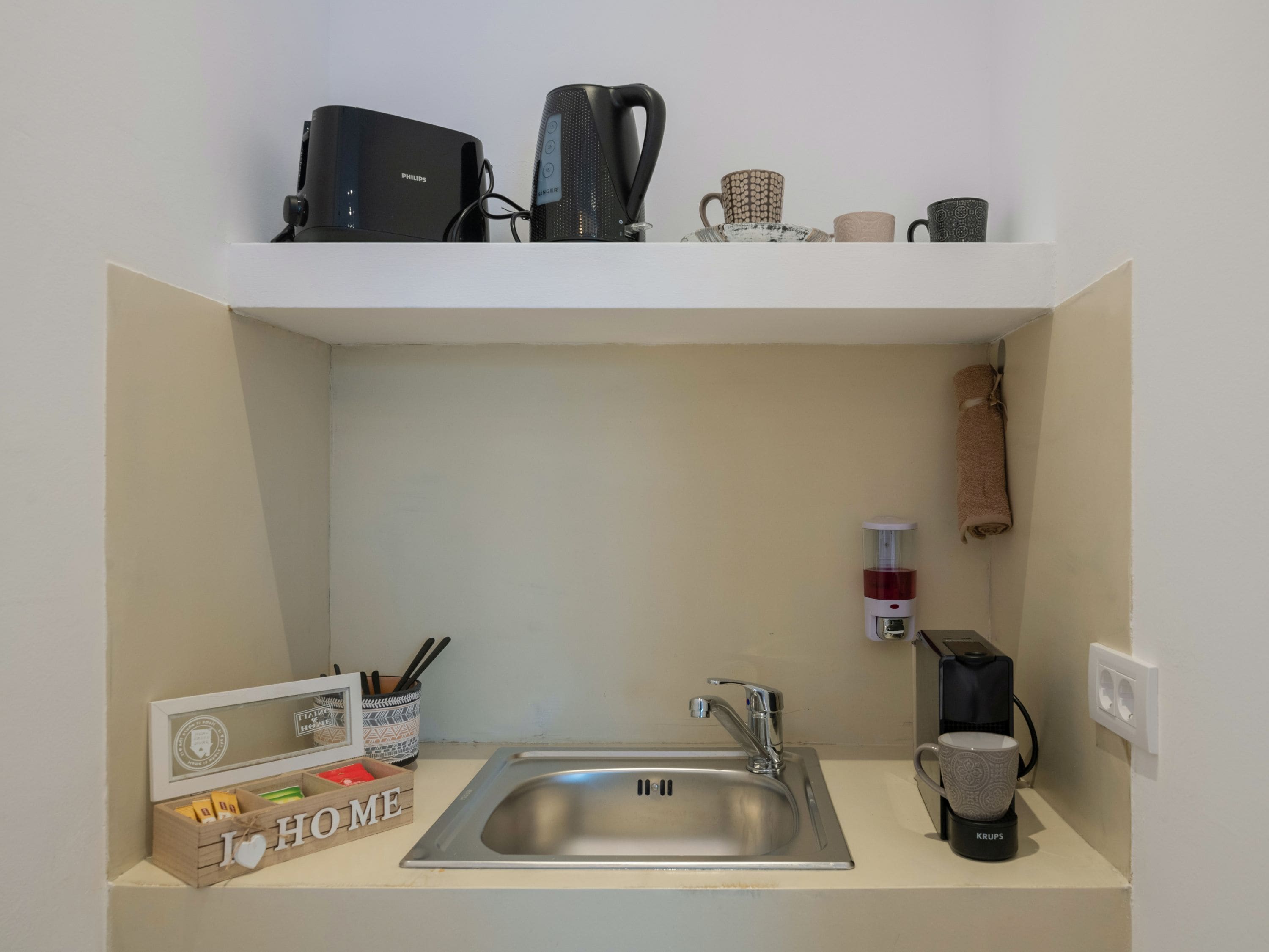 Une cuisine compacte équipée d’un évier, d’une machine à café et d’une petite cafetière posée sur le plan de travail.