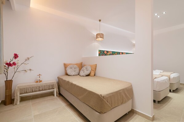 Un dormitorio moderno con una cama, un banco y una pequeña mesa con un florero.