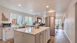 A modern kitchen with white cabinetry, a large island, and a view to a balcony.