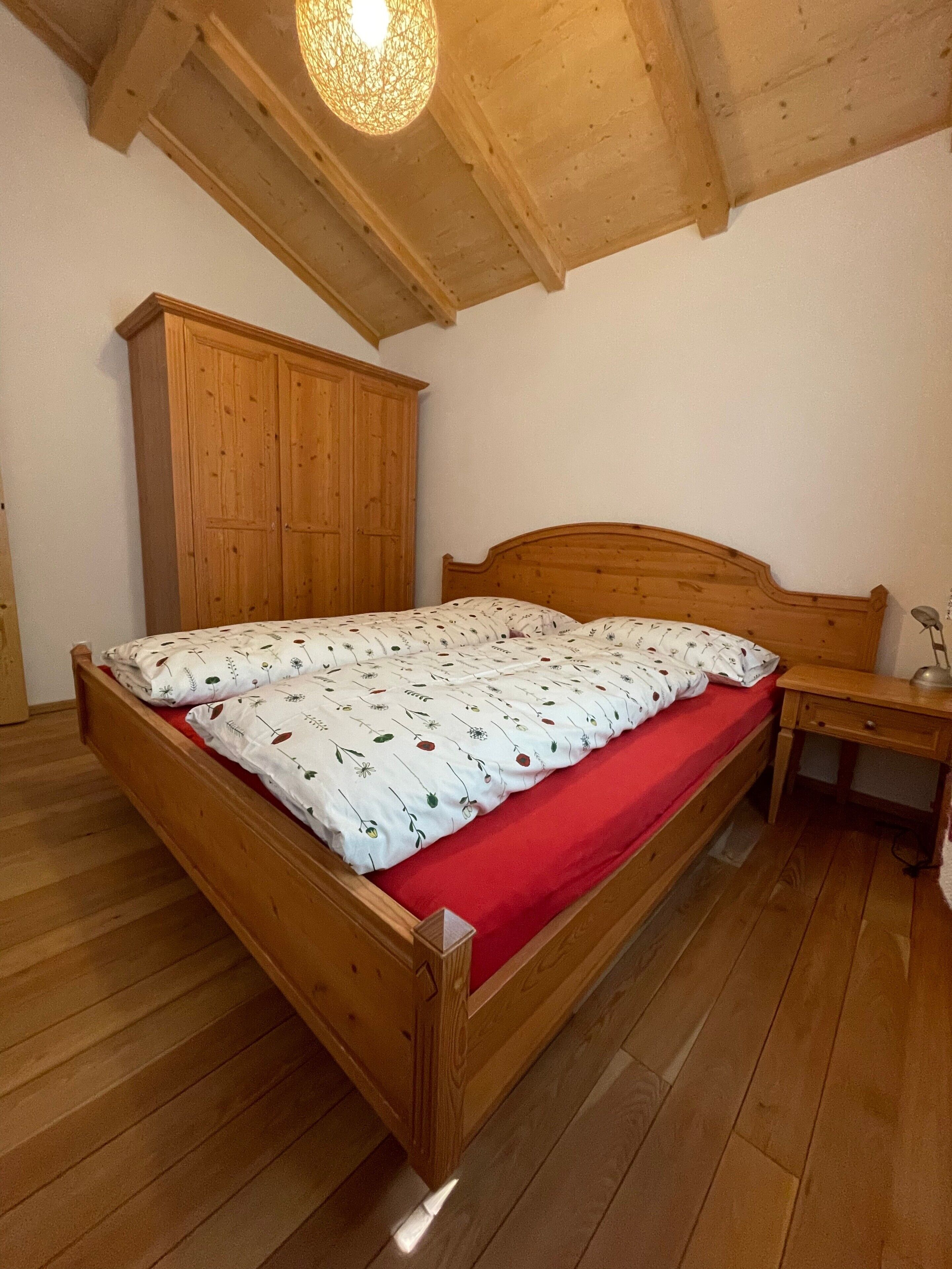 Una camera da letto con un letto e un armadio in legno, una scrivania e una lampada a sospensione.