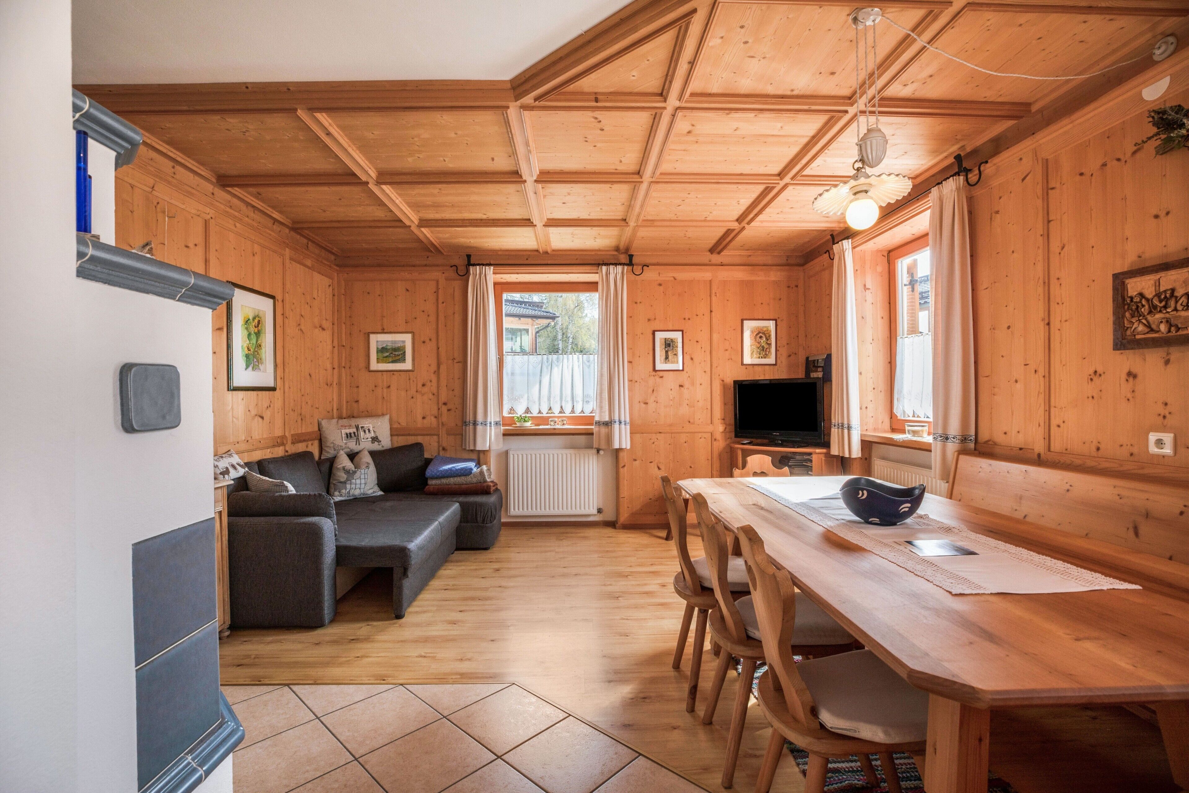 Un interior de madera con sofá, mesa, sillas y televisor.