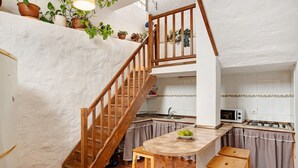 A kitchen with a wooden staircase, a dining table, and a small kitchen island. - Vacation Home 'Mirador de la Abuela' with Sea View, 2 Terraces & Wi-Fi (Gáldar)