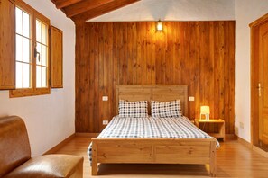 Une chambre à coucher aux murs lambrés, avec un lit, une table de chevet et une chaise.