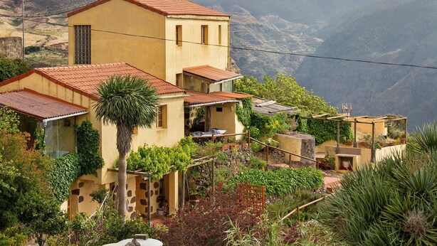 A hillside house with a red-tiled roof, a small balcony, and a garden with various plants. - Vacation Home 'Mirador de la Abuela' with Sea View, 2 Terraces & Wi-Fi (Gáldar)