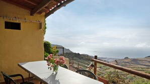 A balcony with a table, chairs, and a vase of flowers. - Vacation Home 'Mirador de la Abuela' with Sea View, 2 Terraces & Wi-Fi (Gáldar)