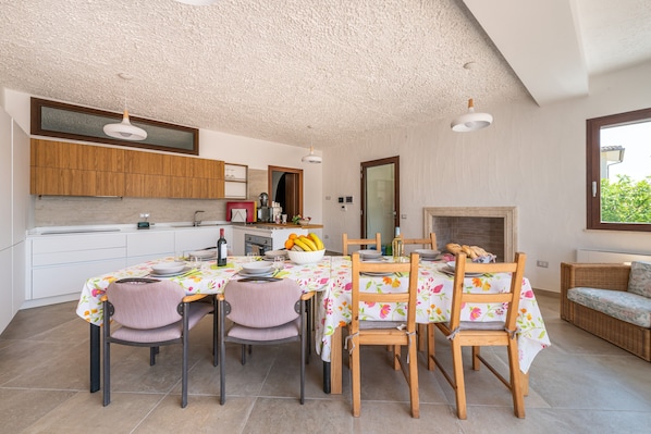 A modern kitchen with wooden cabinets, a dining table with floral tablecloths, and a built-in oven.