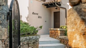 A stone wall, a metal gate, and a building entrance with steps leading up to a door. - Villa Casa Soleada with Sea View, Pool, Terraces & Wi-Fi (Capdepera)