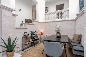 Un interior moderno con una mesa de comedor, sillas, un sofá, una escalera pequeña y un balcón.
