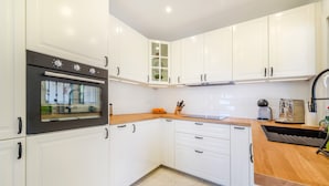 A kitchen with white cabinets, a wooden countertop, a built-in oven, and a toaster. - Villa Casa Soleada with Sea View, Pool, Terraces & Wi-Fi (Capdepera)