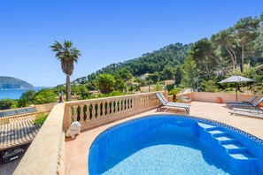 A swimming pool with a view of the sea, a palm tree, and a statue.