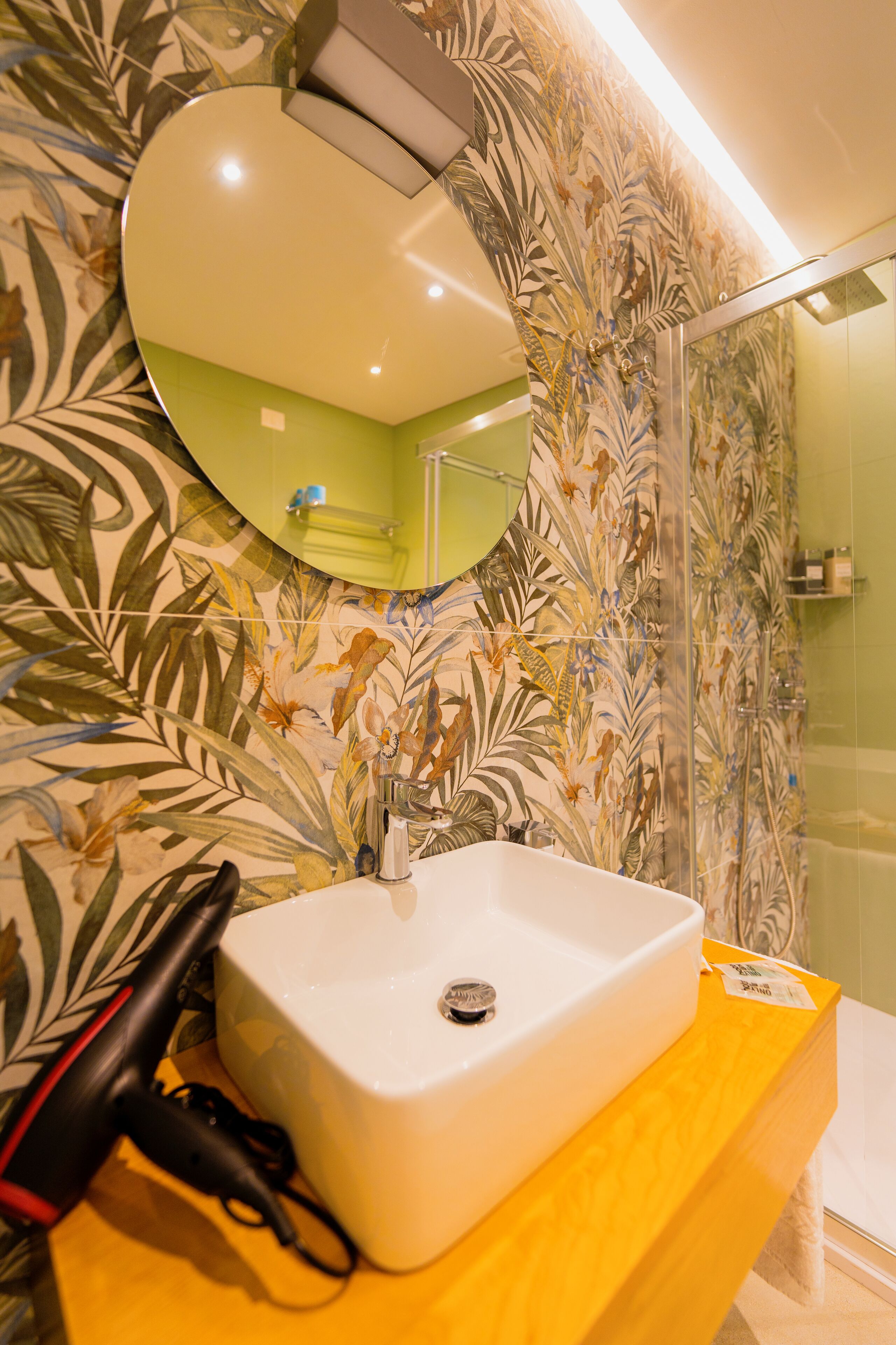 Un baño con lavamanos blanco, espejo y ducha.