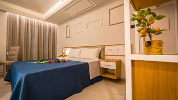 Una habitación de hotel con cama, mesita de noche, silla y una planta.
