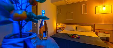 A hotel room with a bed, bedside table, and a vase with flowers.